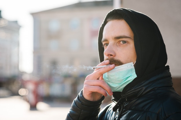 closeup-man-with-mask-during-covid-19-pandemic-smoking-cigarette-street_180731-34